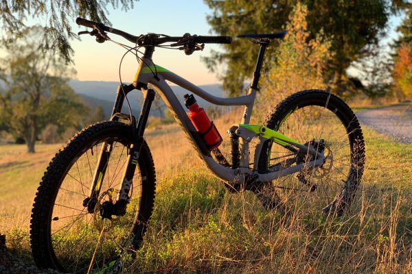 Mountain Bike Fahrrad bei Sonnenuntergang auf einer Wiese mit Grass und Bäumen
